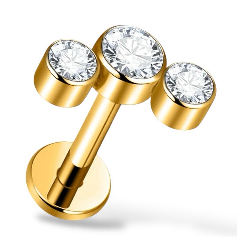 Labret-Ohrring aus Titan und Gold mit drei Zirkonen.